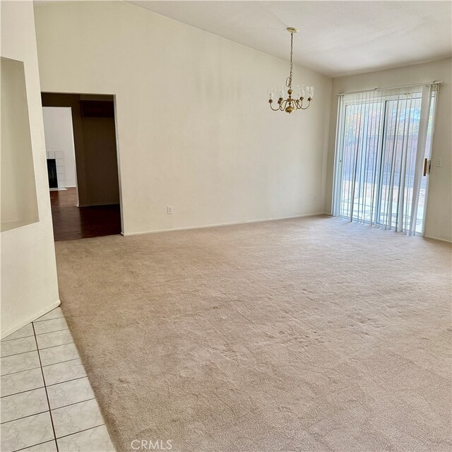 unfurnished room featuring a chandelier and light colored carpet