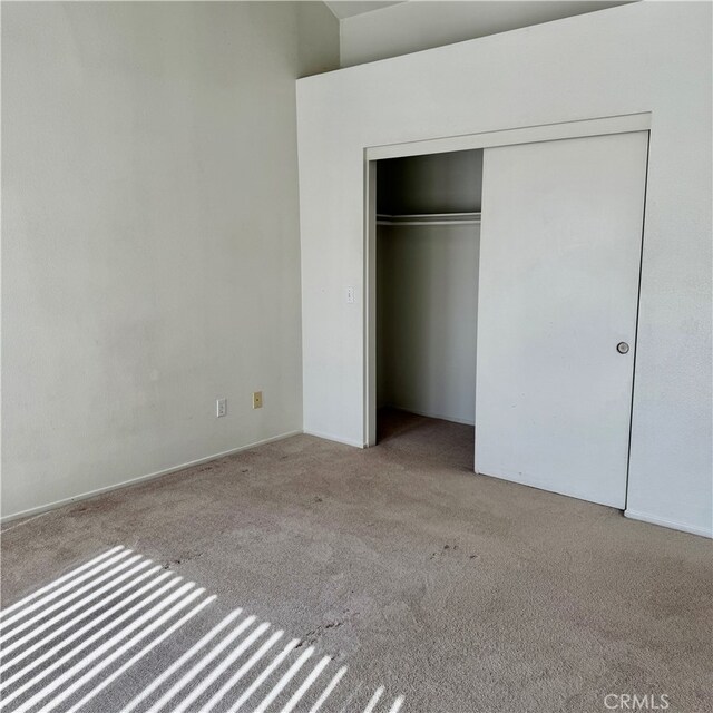 unfurnished bedroom featuring light carpet and a closet