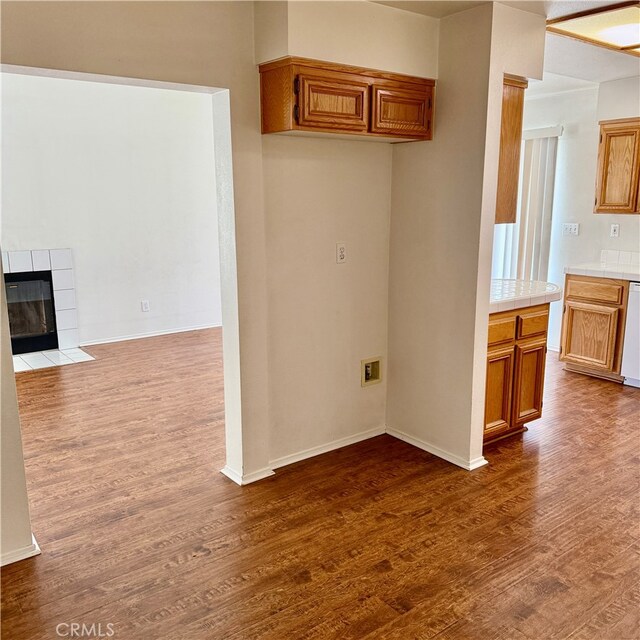 kitchen with dishwasher, hardwood / wood-style flooring, and a tiled fireplace