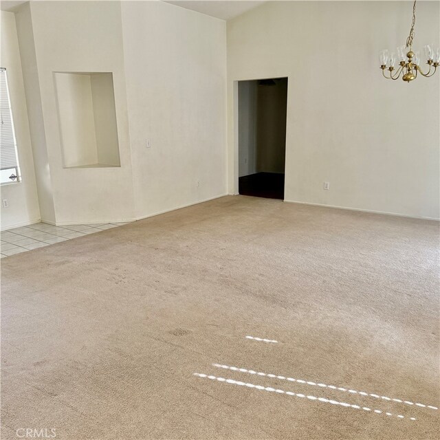 carpeted empty room with a notable chandelier