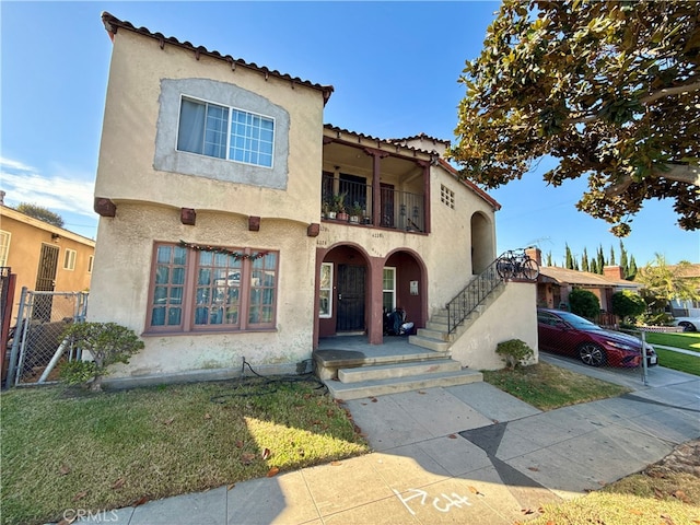 mediterranean / spanish-style house with a balcony and a front lawn