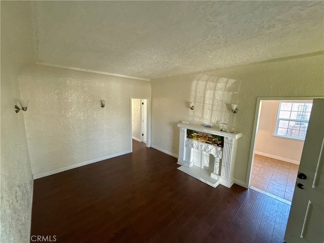 unfurnished living room featuring a textured ceiling and dark hardwood / wood-style floors