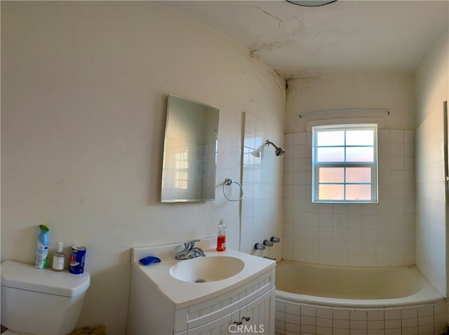 full bathroom with tiled shower / bath, vanity, and toilet