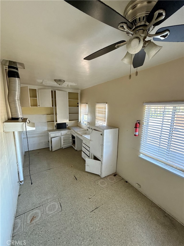 kitchen featuring a wealth of natural light, sink, white cabinetry, and ceiling fan