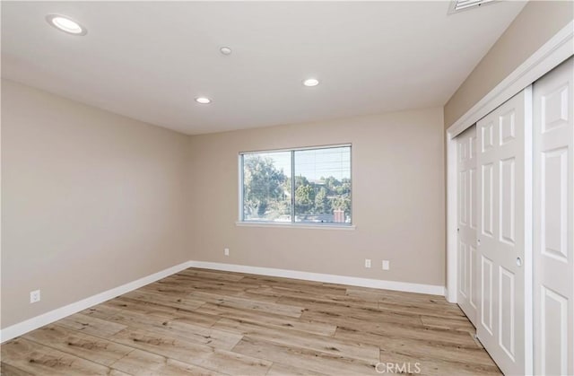 unfurnished bedroom with a closet and light wood-type flooring