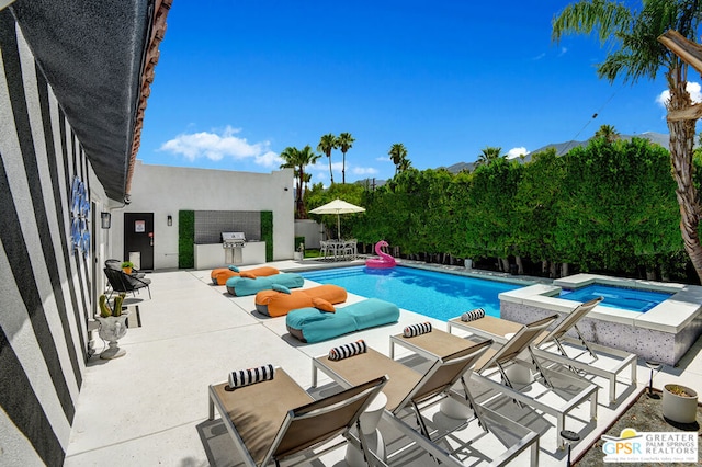 view of swimming pool featuring an in ground hot tub, a patio, and exterior kitchen