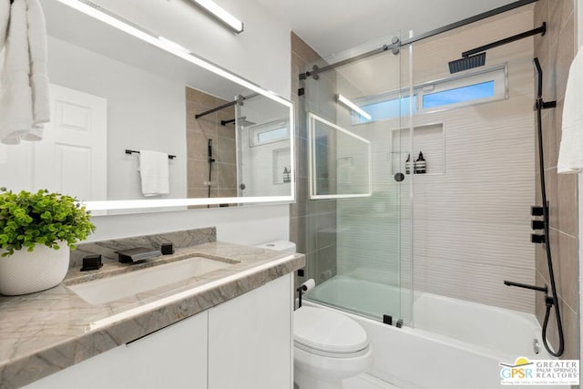 full bathroom with combined bath / shower with glass door, vanity, and toilet