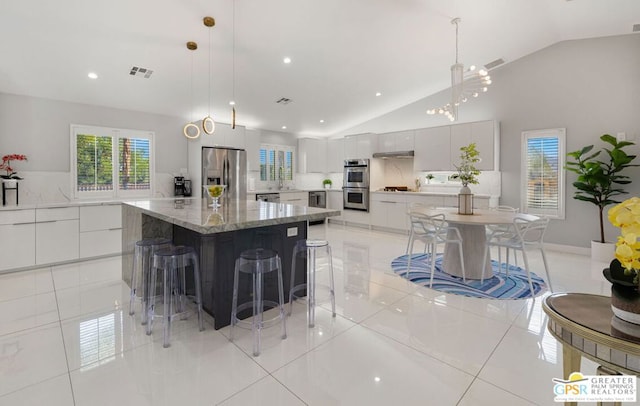 kitchen with pendant lighting, a spacious island, vaulted ceiling, a breakfast bar area, and appliances with stainless steel finishes