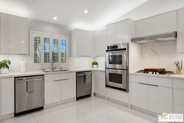 kitchen with white cabinetry, sink, stainless steel appliances, tasteful backsplash, and vaulted ceiling