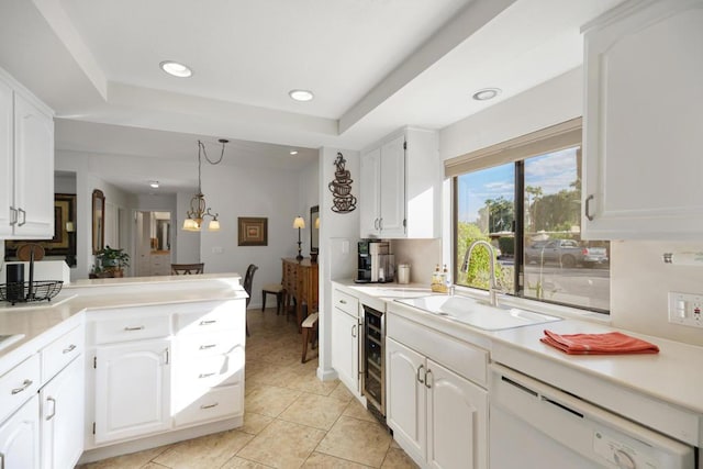 kitchen featuring pendant lighting, dishwasher, white cabinets, sink, and a chandelier