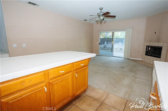 kitchen with tile countertops, light carpet, and a fireplace