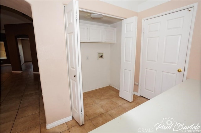 interior space featuring washer hookup, light tile patterned flooring, and cabinets