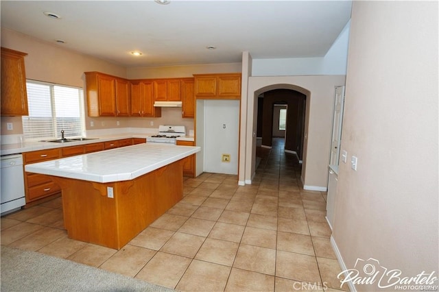 kitchen with white appliances, sink, tile countertops, a center island, and light tile patterned floors