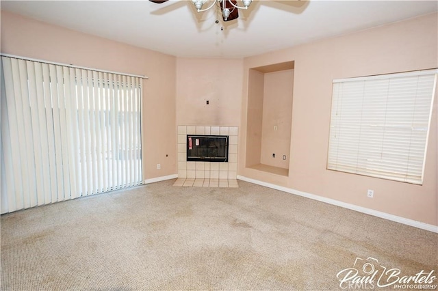 unfurnished living room with ceiling fan, carpet, and a fireplace