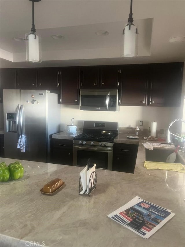 kitchen featuring dark brown cabinets, sink, stainless steel appliances, and decorative light fixtures