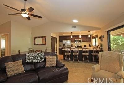 tiled living room featuring ceiling fan and vaulted ceiling