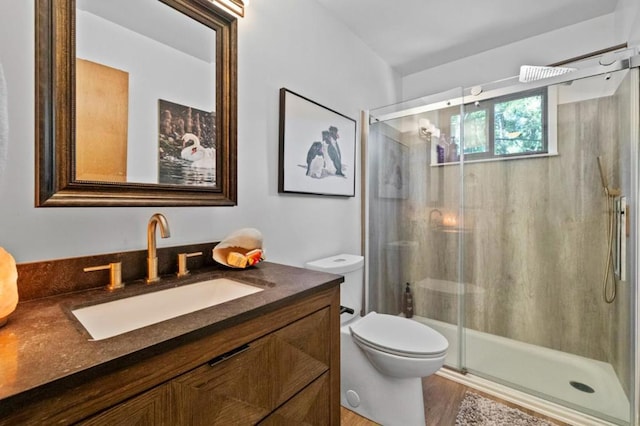 bathroom featuring toilet, a shower with shower door, hardwood / wood-style floors, and vanity