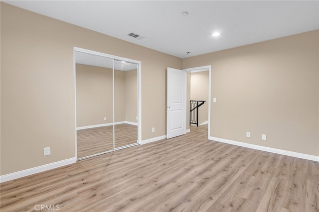 unfurnished bedroom featuring light wood-type flooring, a closet, visible vents, and baseboards