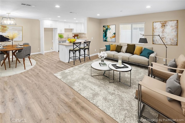 living room featuring recessed lighting, visible vents, baseboards, light wood finished floors, and an inviting chandelier