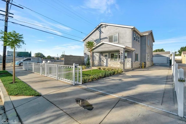 exterior space with a garage, stone siding, a fenced front yard, and stucco siding