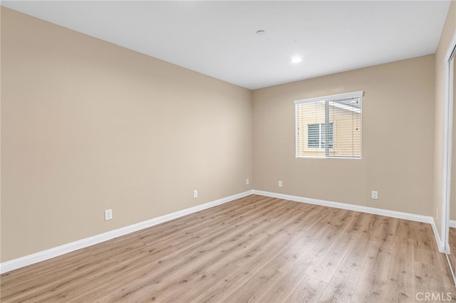 empty room featuring light wood-style floors, recessed lighting, and baseboards