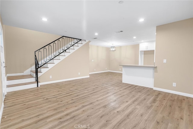 unfurnished living room with stairway, light wood-style flooring, visible vents, and recessed lighting