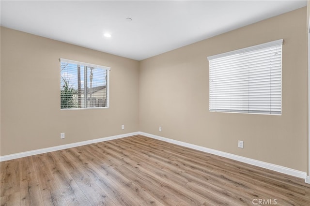 spare room featuring light wood-type flooring, baseboards, and recessed lighting