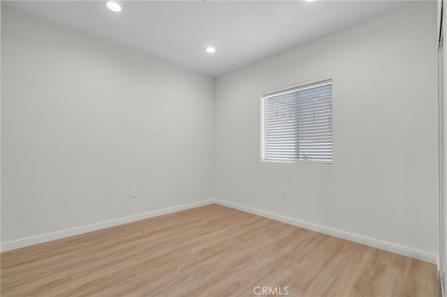 empty room featuring light wood-type flooring, baseboards, and recessed lighting