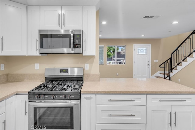 kitchen with visible vents, white cabinets, appliances with stainless steel finishes, a peninsula, and light countertops