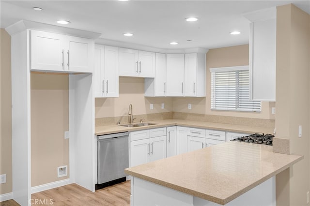 kitchen with appliances with stainless steel finishes, light countertops, a sink, and white cabinetry