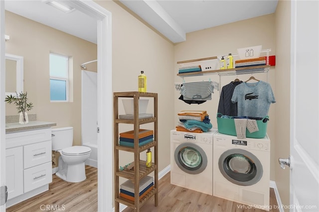 laundry area with laundry area, baseboards, separate washer and dryer, and light wood finished floors