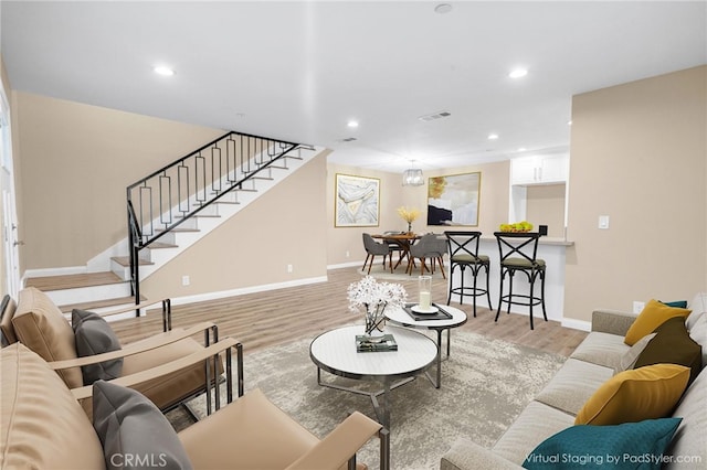 living area with light wood finished floors, recessed lighting, visible vents, stairway, and baseboards