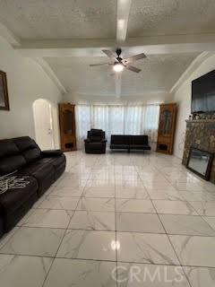 unfurnished living room with beam ceiling, a fireplace, and ceiling fan