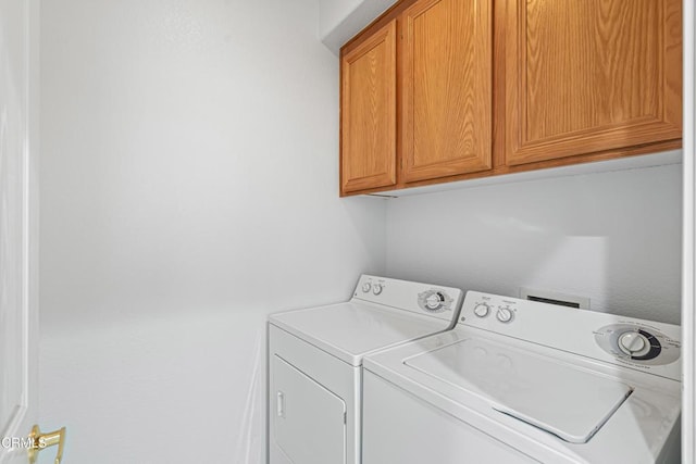 clothes washing area with washer and dryer and cabinets