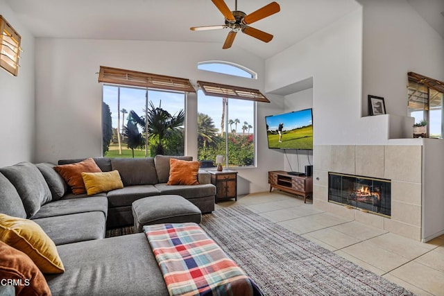 living room with ceiling fan, a fireplace, light tile patterned flooring, and high vaulted ceiling