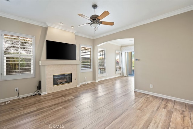 unfurnished living room featuring ceiling fan, a fireplace, ornamental molding, and light wood-type flooring