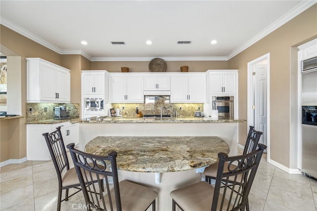 kitchen featuring decorative backsplash, appliances with stainless steel finishes, ornamental molding, a spacious island, and white cabinetry