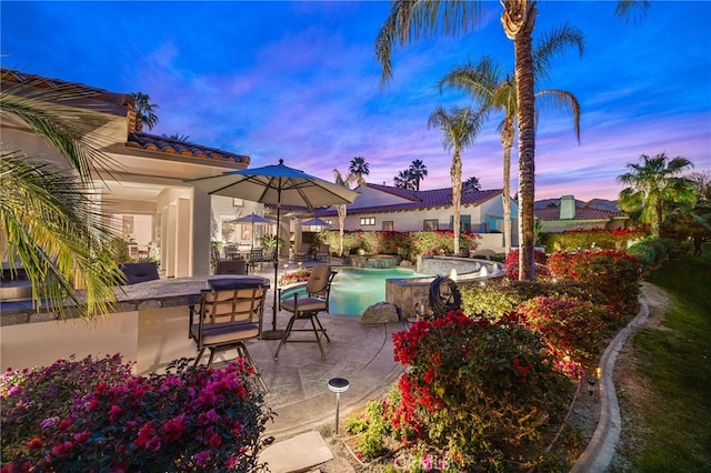 patio terrace at dusk with a swimming pool with hot tub