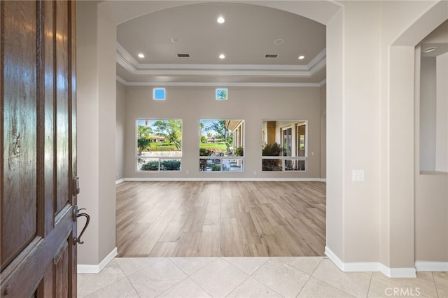 interior space with light hardwood / wood-style floors, a raised ceiling, and ornamental molding