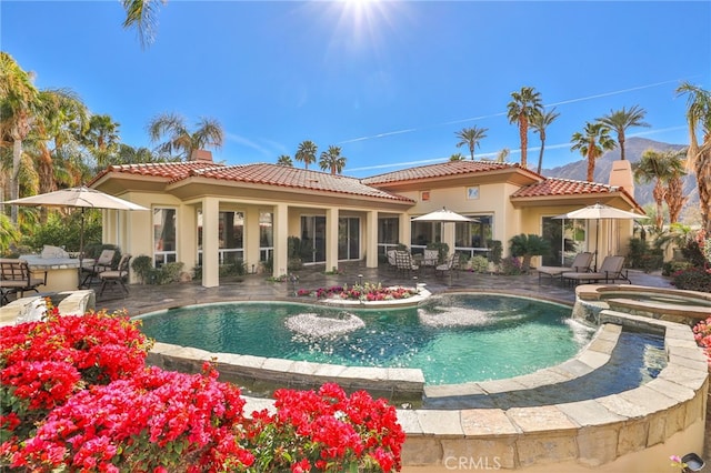 back of property featuring a patio area, pool water feature, and a pool with hot tub