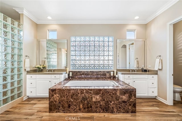 bathroom featuring vanity, wood-type flooring, ornamental molding, and tiled tub