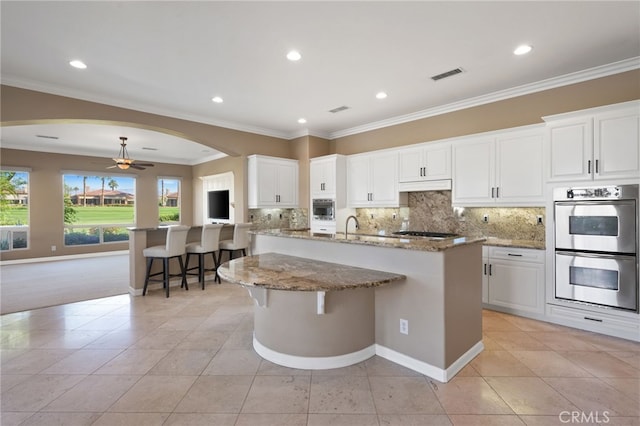 kitchen featuring a breakfast bar, white cabinetry, an island with sink, and appliances with stainless steel finishes