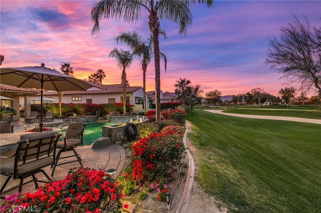 view of property's community with a patio area and a lawn