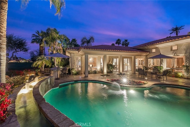 pool at dusk with a patio area