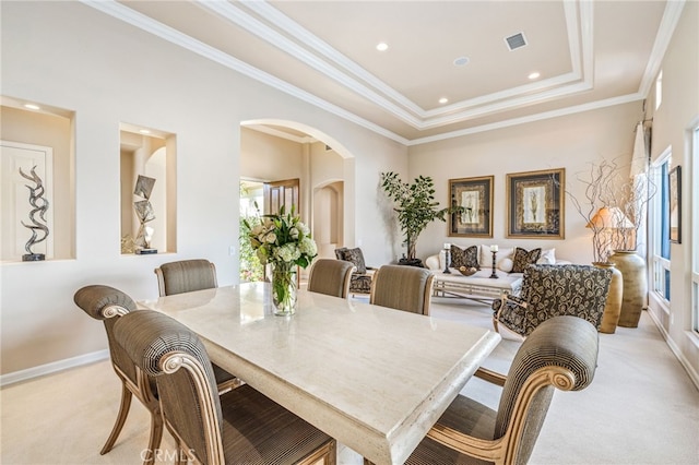 carpeted dining area featuring a tray ceiling and crown molding