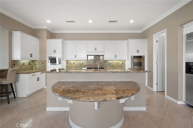 kitchen with tasteful backsplash, an island with sink, stone countertops, and appliances with stainless steel finishes