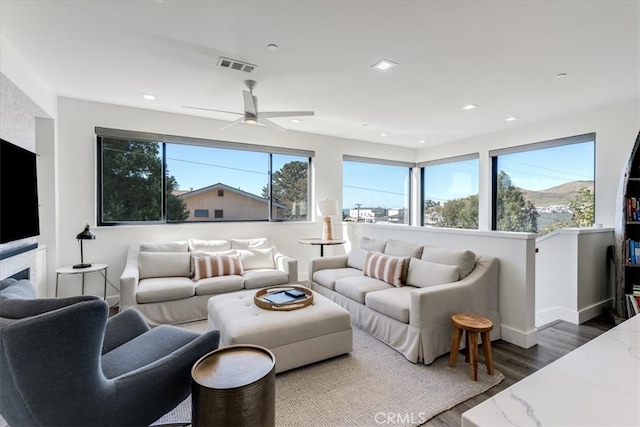 living room with dark wood-type flooring, a healthy amount of sunlight, and ceiling fan