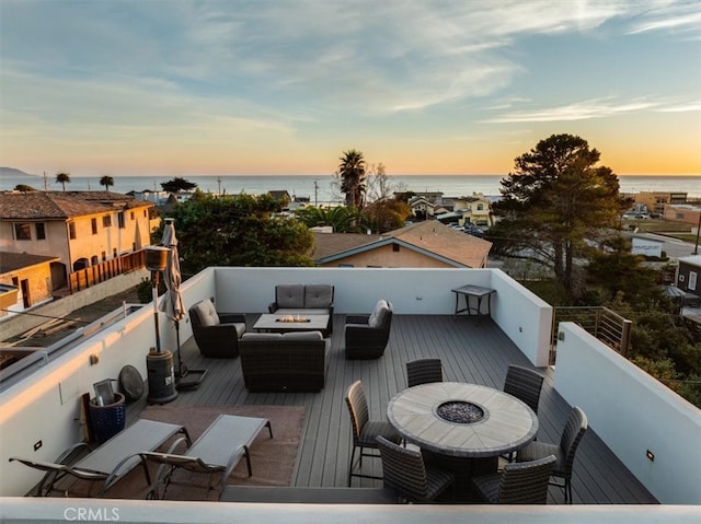 deck at dusk with outdoor lounge area and a water view