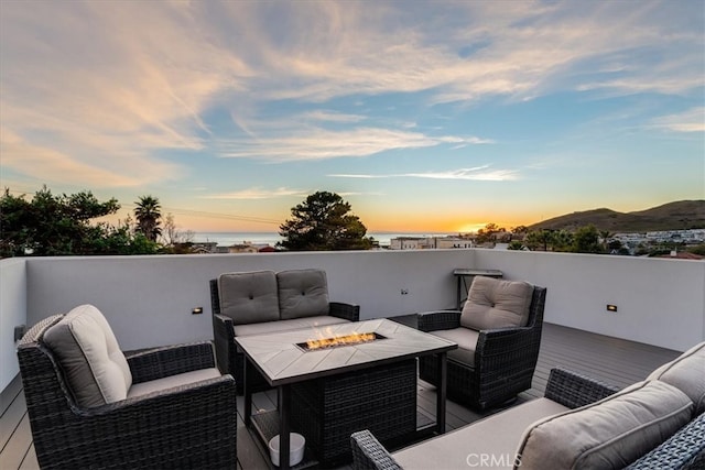 deck at dusk featuring a mountain view and an outdoor living space with a fire pit