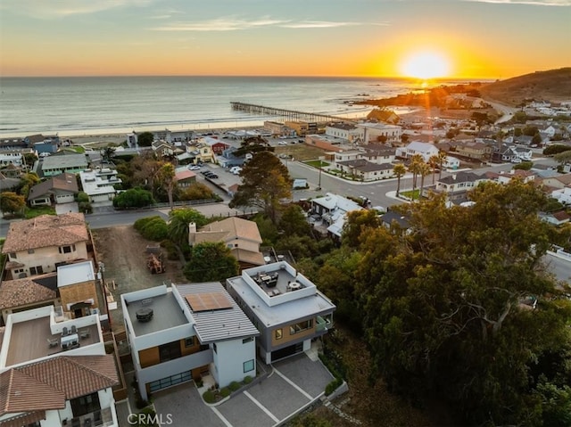 aerial view at dusk featuring a water view